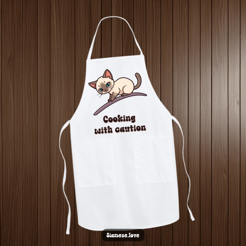 Funny apron with a sleek Siamese cat elegantly balancing on a narrow, curving surface, perfect for kitchen fun and as a humorous gift.