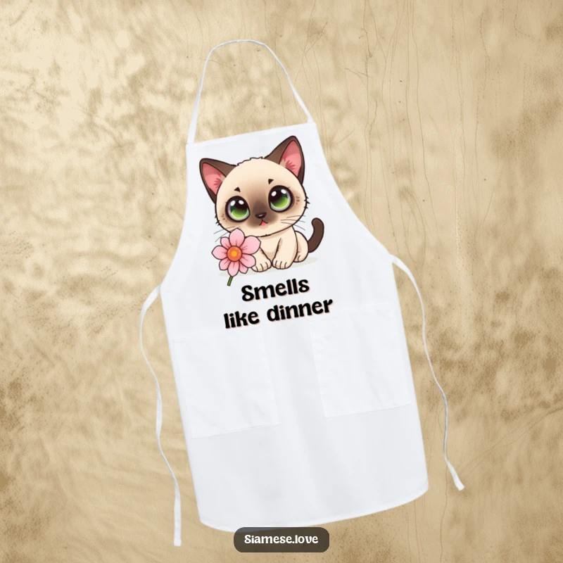 Funny kawaii Siamese cat with wide eyes sniffing a flower on a kitchen apron, adding charm to cooking.