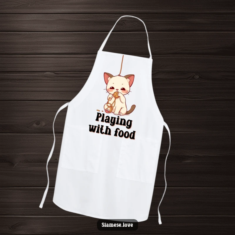 Funny apron featuring a cute kawaii Siamese cat batting playfully at a dangling yarn ball, perfect for kitchen antics.