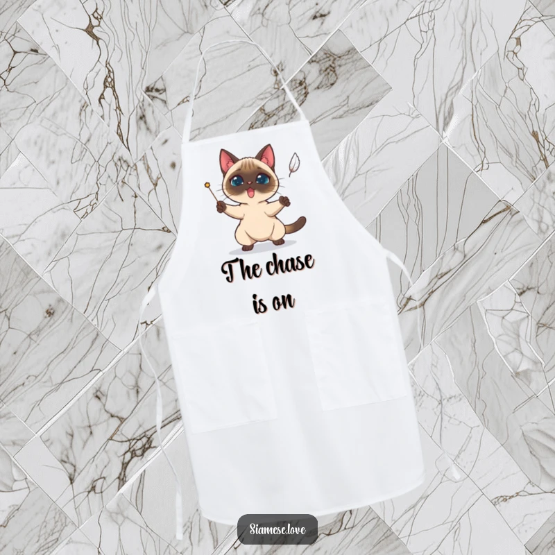 Funny Siamese cat character determinedly trying to catch a falling feather on a kitchen apron.