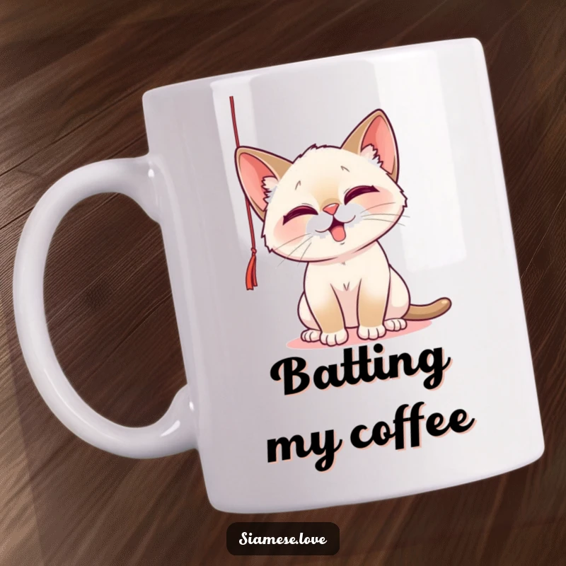 Funny Mug featuring a playful Siamese cat with mischievous eyes, batting at a dangling string, capturing feline curiosity and fun.