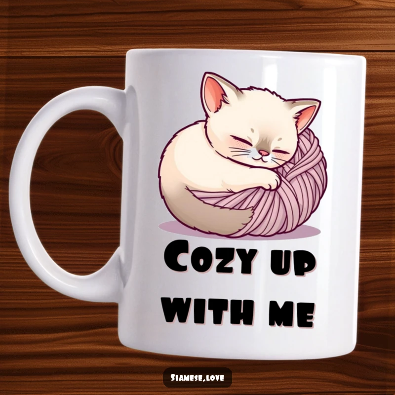 Funny Siamese cat mug, a contented feline is peacefully curled up inside a large ball of yarn, showcasing coziness.