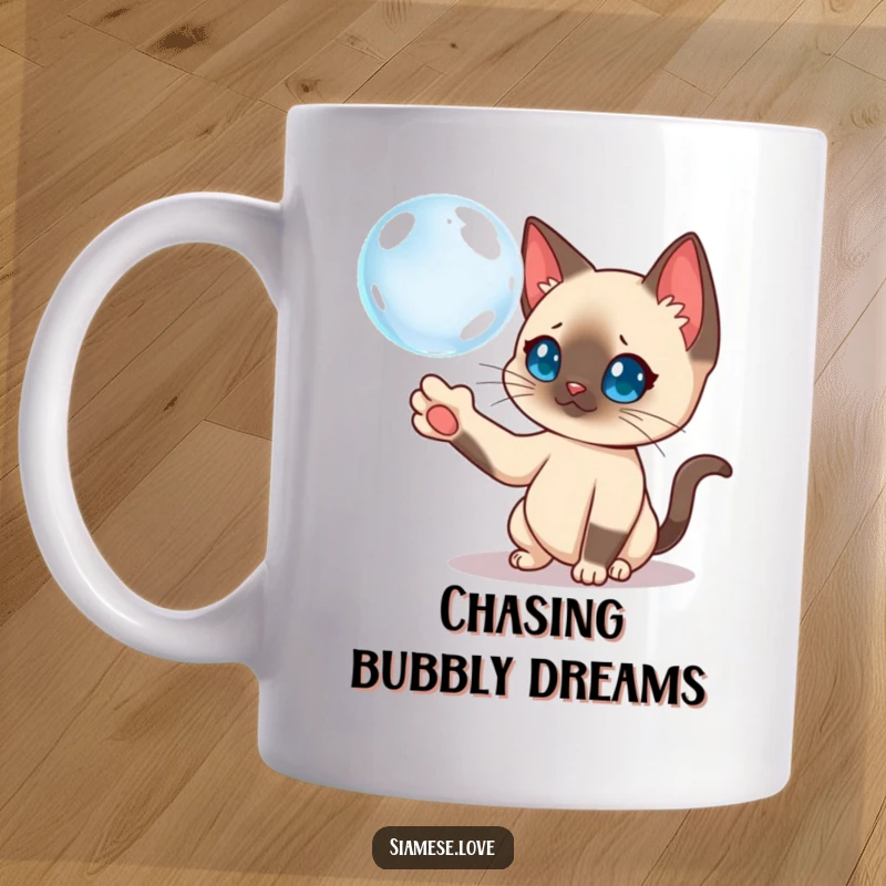 Funny Siamese cat curiously batting a floating bubble with its paw on this playful mug.