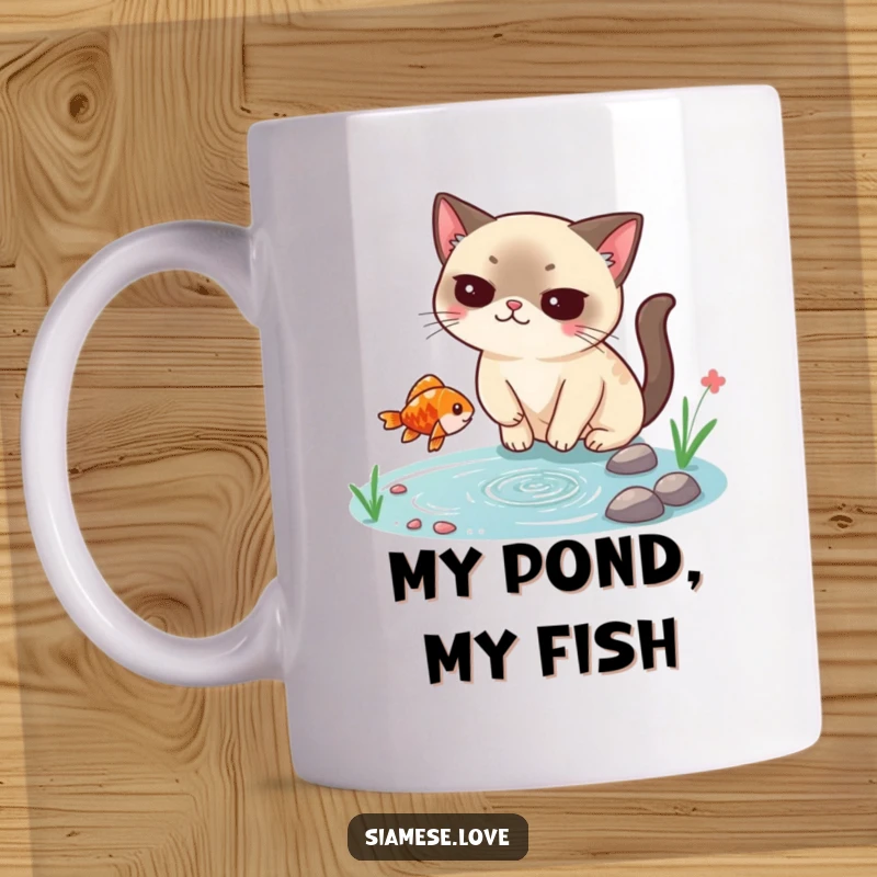 Funny Siamese cat mug, smugly catching a falling fish from a tiny pond, showcasing feline superiority and a hilarious fishing moment.