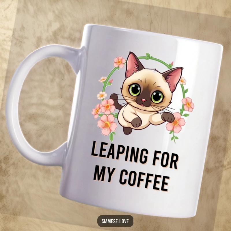 Funny mug featuring a curious Siamese cat with wide eyes leaping through a hoop of colorful flowers, embodying elegance and playful charm.