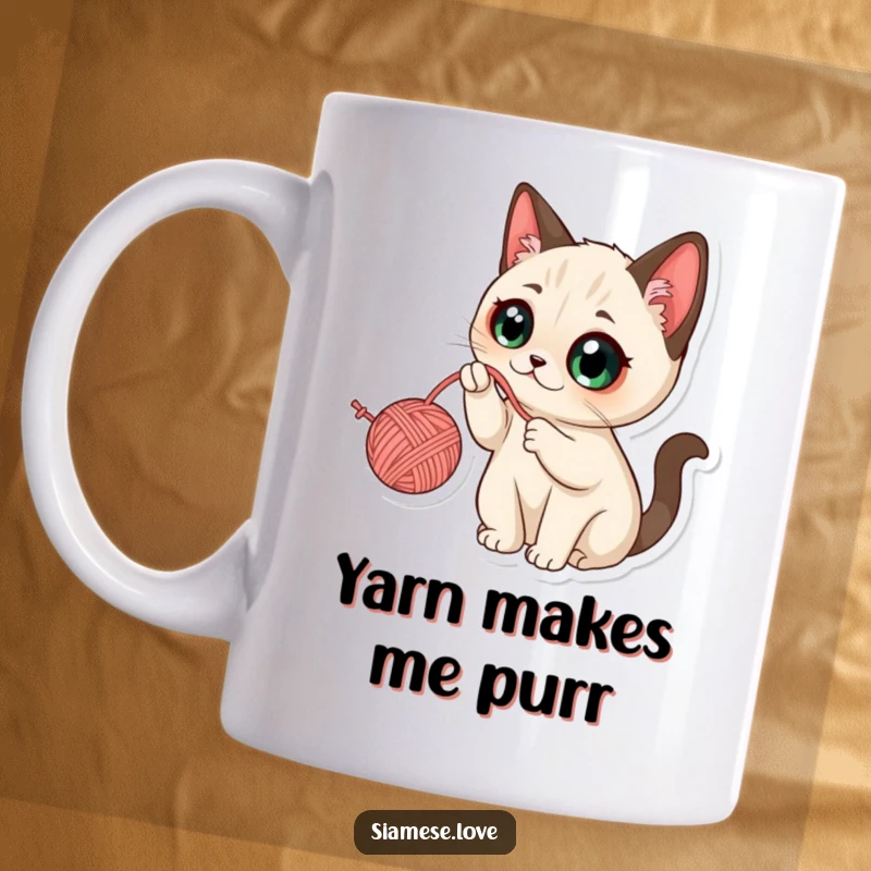 Funny Kawaii Siamese Cat Mug: Cute cat with wide eyes, playfully batting at a dangling ball of yarn, full of mischief.