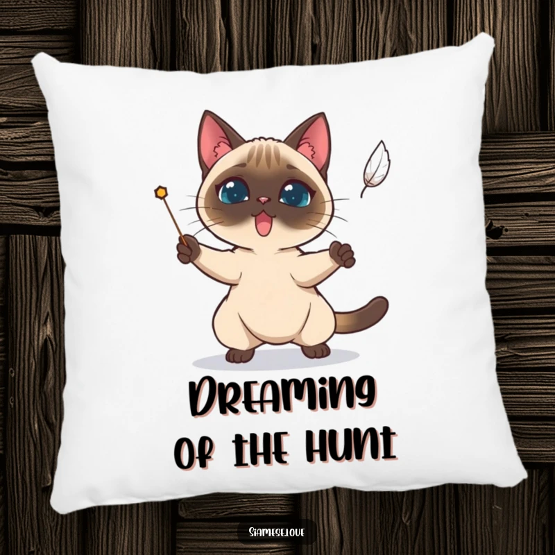 Funny Siamese cat determinedly trying to catch a falling feather on a decorative pillow.