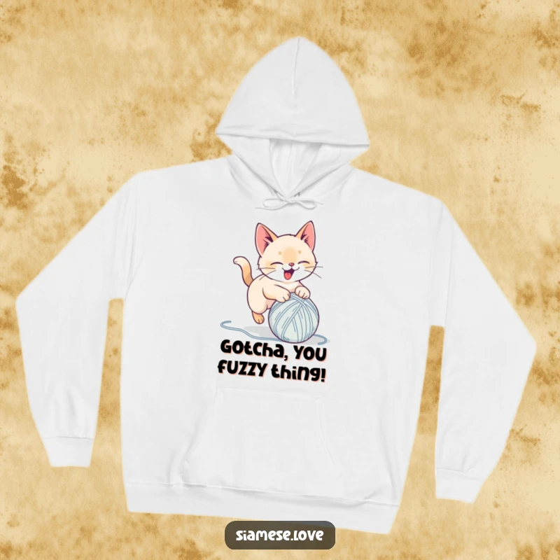 Funny hoodie with a stylized Siamese cat delightedly pouncing on a yarn ball, offering cozy comfort and playful humor for a great gift.