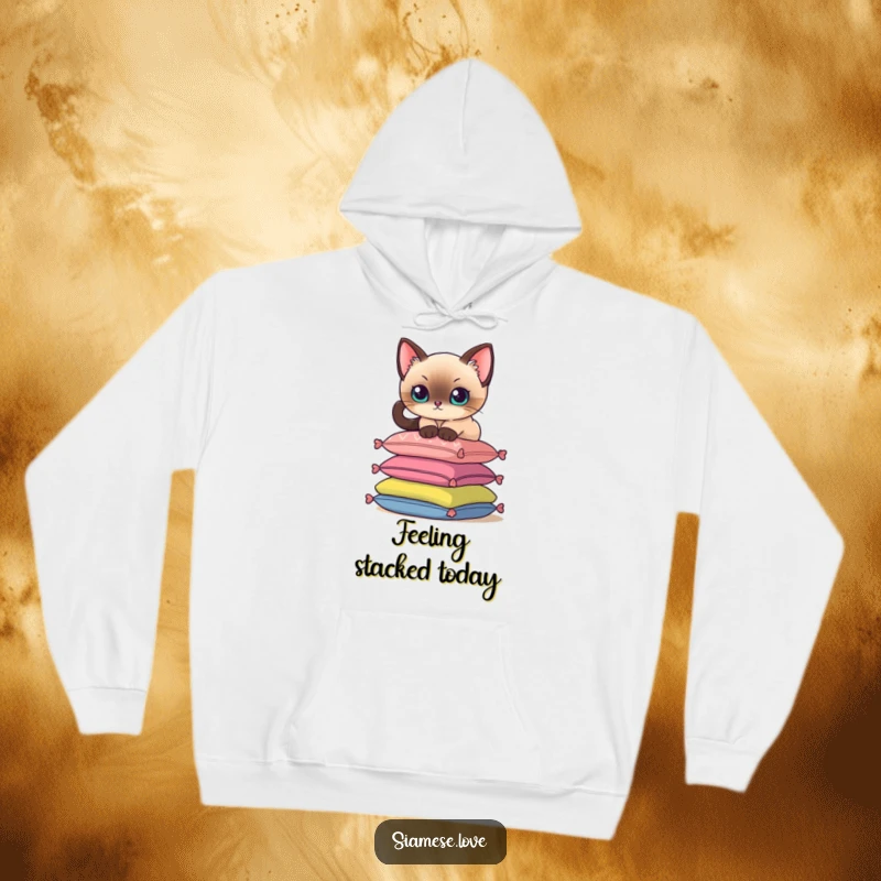 Funny hoodie featuring a Siamese cat delicately perching on a stack of colorful cushions, offering cozy feline vibes.