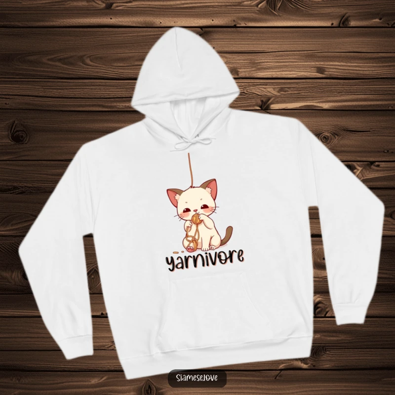 Funny hoodie depicting a cute kawaii Siamese cat batting playfully at a dangling ball of yarn, embodying cozy fun.
