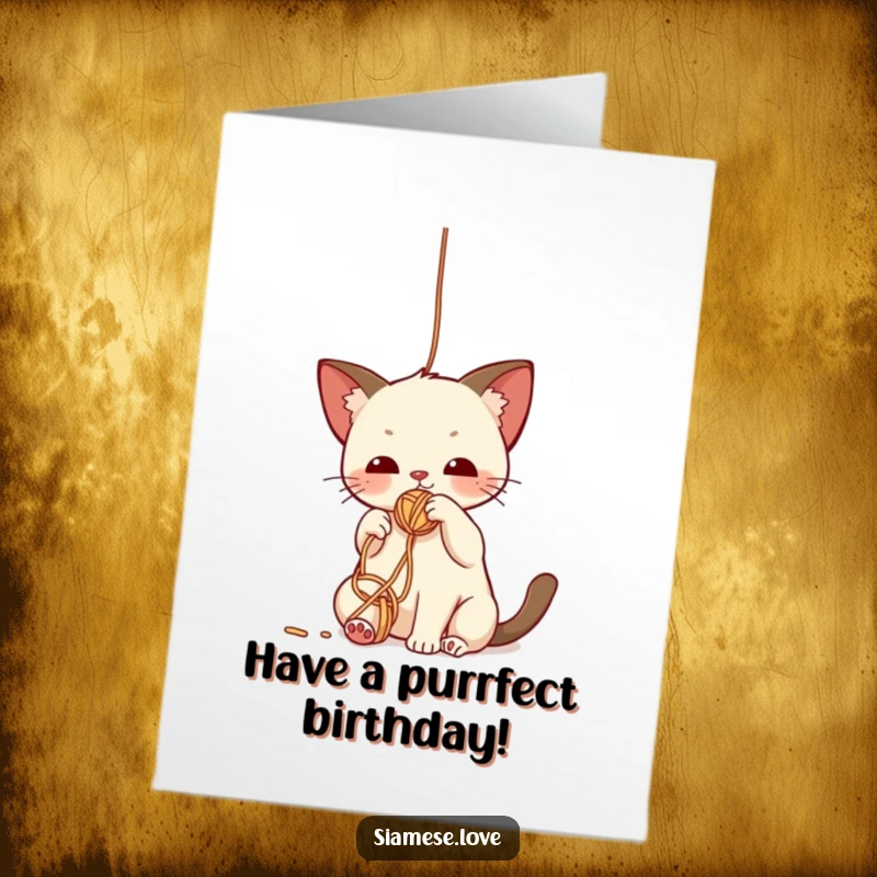 Funny Free Printable Birthday Card: Cute kawaii Siamese cat batting playfully with its paw at a colorful dangling yarn ball.