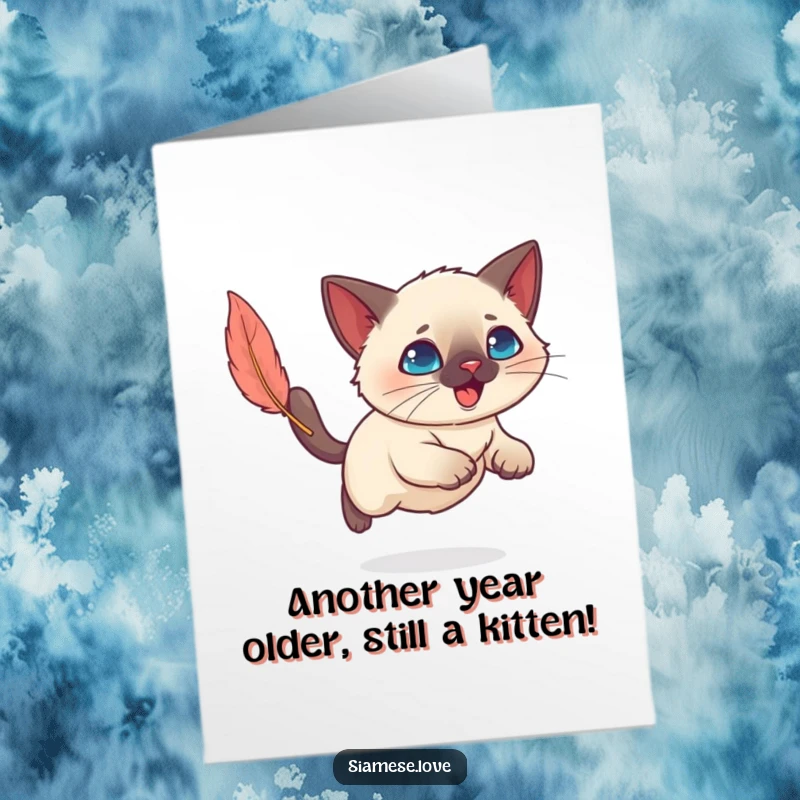 Funny Free Printable Birthday Card: Kawaii Siamese cat joyfully pounces on a feather toy, celebrating with playful energy.