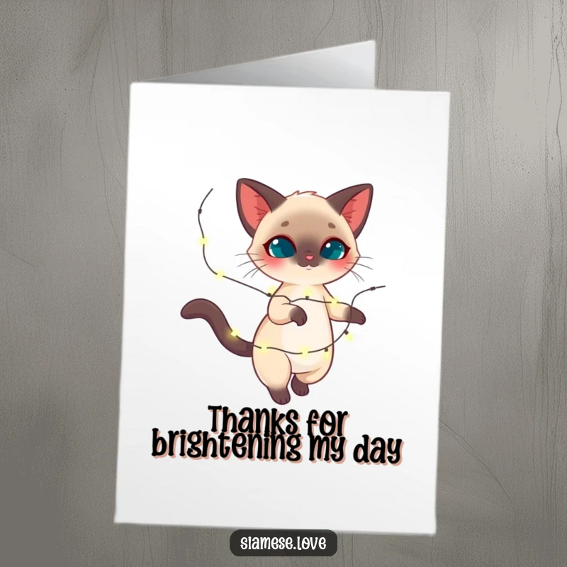 Funny Free Printable Thank You Card: A charming Siamese cat gracefully twirls with a garland of bright, twinkling lights, expressing thanks.