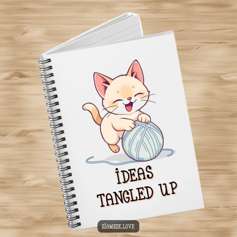Funny notebook with a stylized Siamese cat delightedly pouncing on a yarn ball, perfect for jotting notes and as a humorous gift.