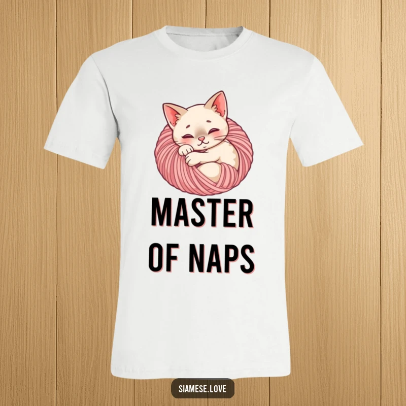 Funny Siamese cat t-shirt depicting a content feline sleeping peacefully within a large ball of yarn, a cozy design.