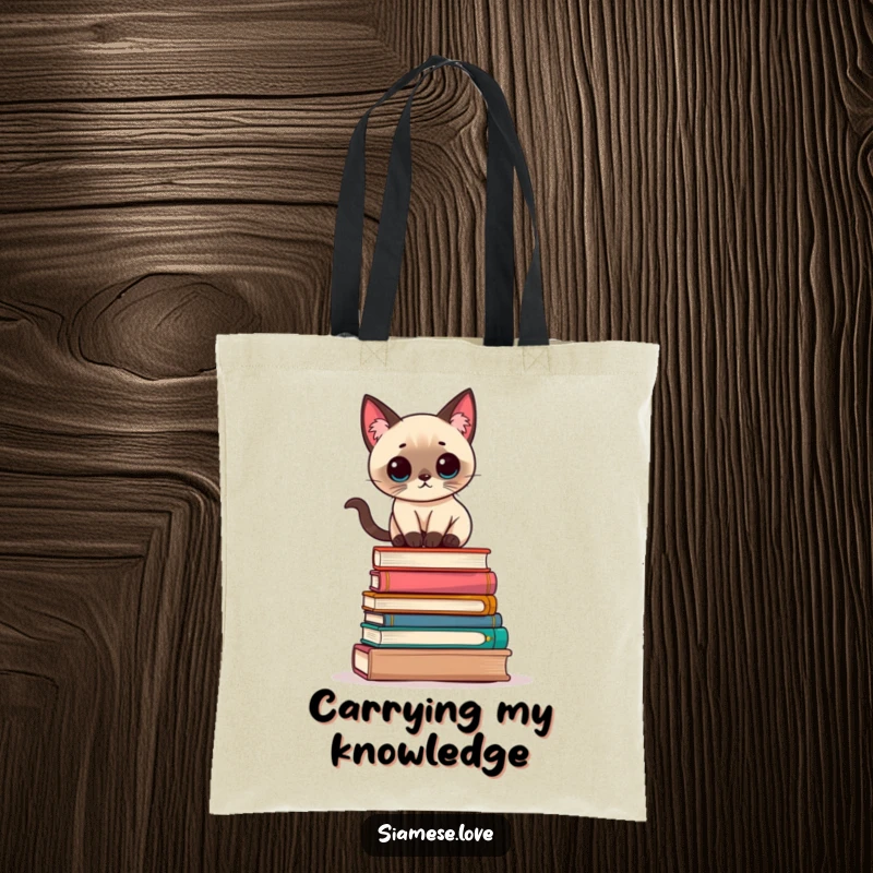 Funny Kawaii Siamese cat balancing precariously on a stack of books on a durable tote bag, ideal for carrying essentials.