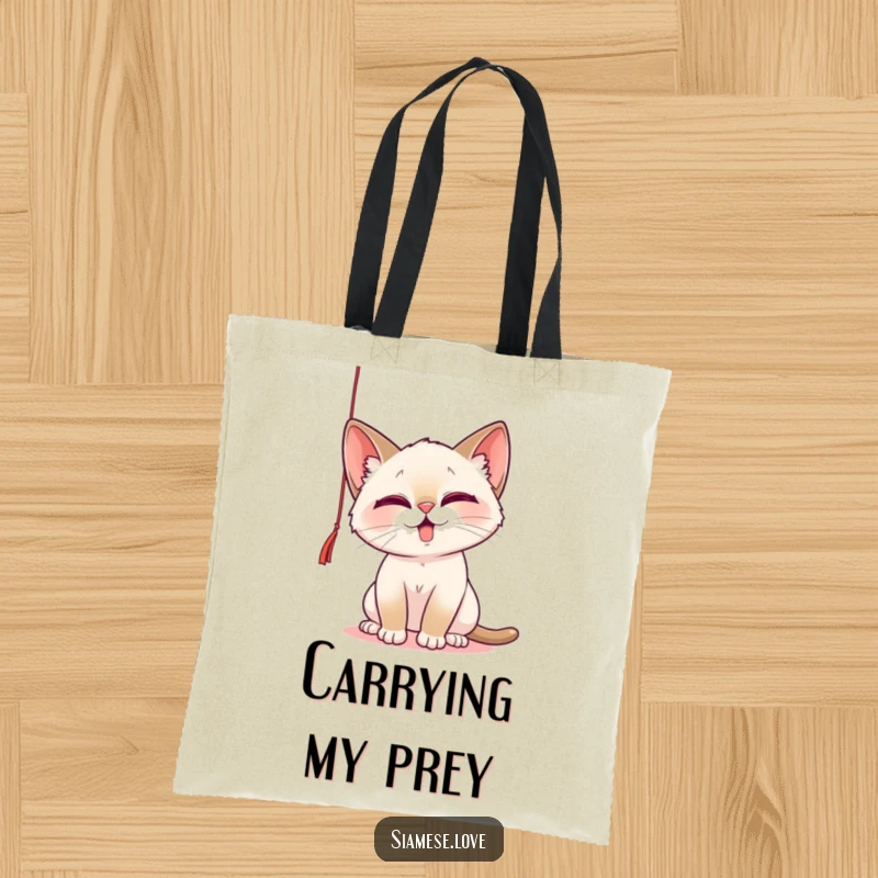 Funny Tote Bag with a playful Siamese cat batting at a dangling string, perfect for carrying items with feline charm and humor.