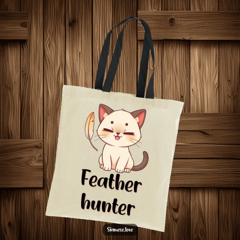Funny cute Siamese cat tote bag with a mischievous grin, batting playfully at a feather, a cute and practical accessory.