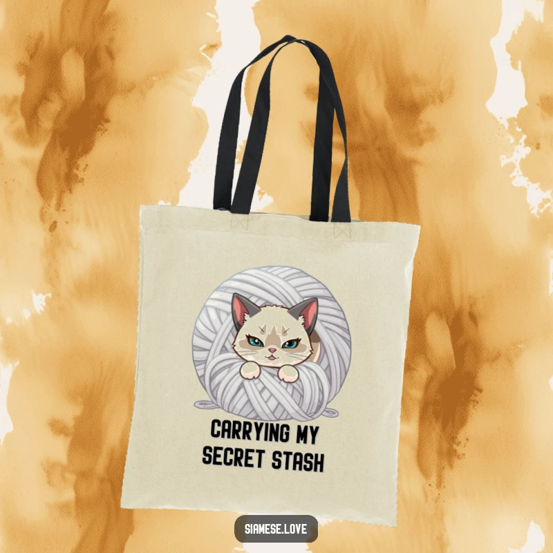 Funny tote bag featuring a Siamese cat with a mischievous smirk, hiding behind a giant ball of yarn. Practical and cute.