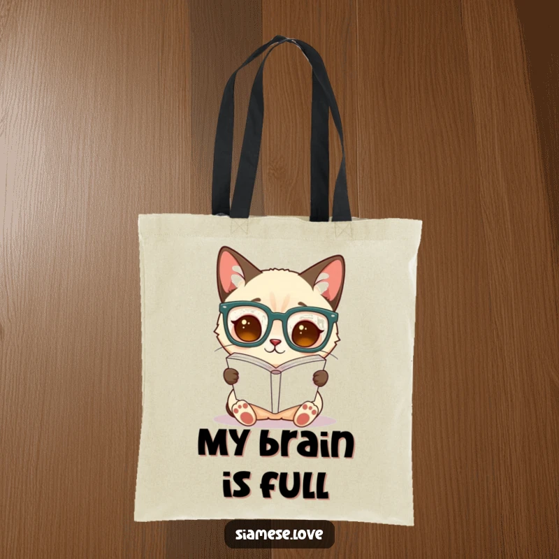 Funny Siamese cat tote bag, a feline with large glasses reads an inverted book, perfect for carrying literary treasures.
