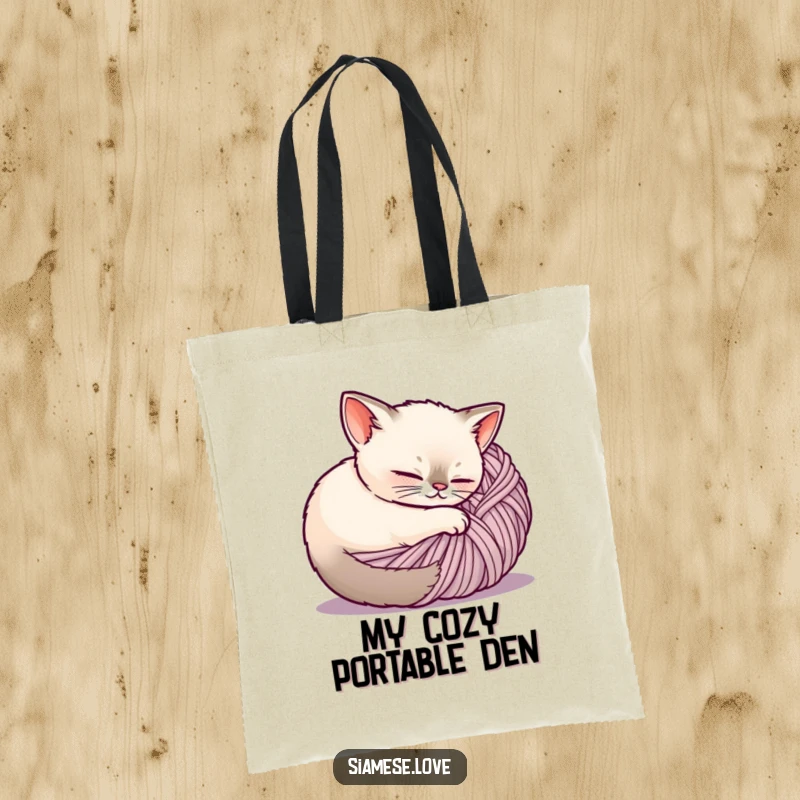 Funny Siamese cat tote bag, a content cat is comfortably nestled within a ball of yarn, perfect for carrying cozy items.