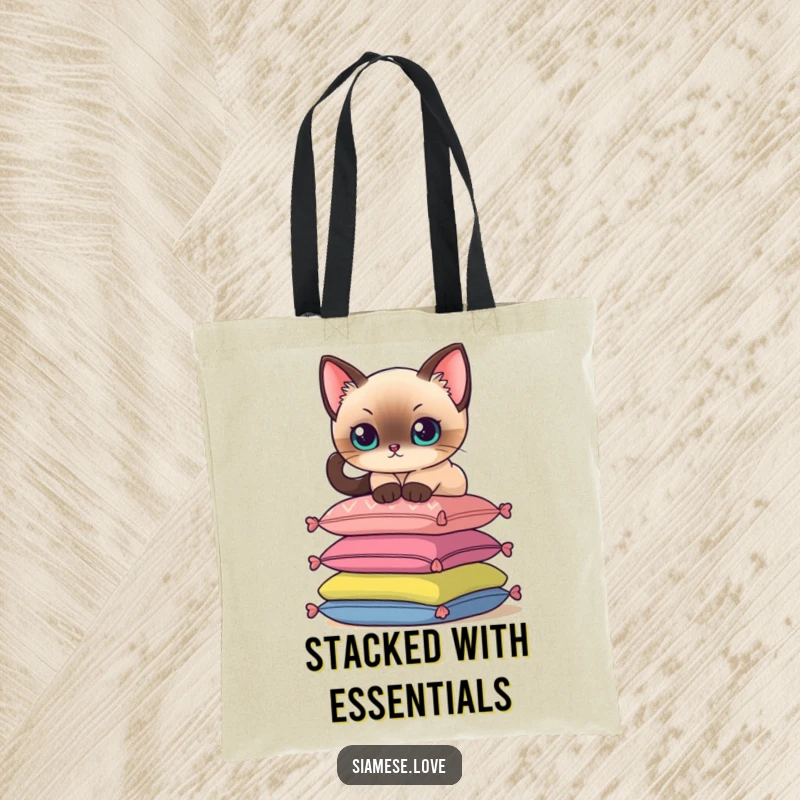 Funny tote bag depicting a Siamese cat delicately balancing on a stack of colorful cushions, great for shopping.